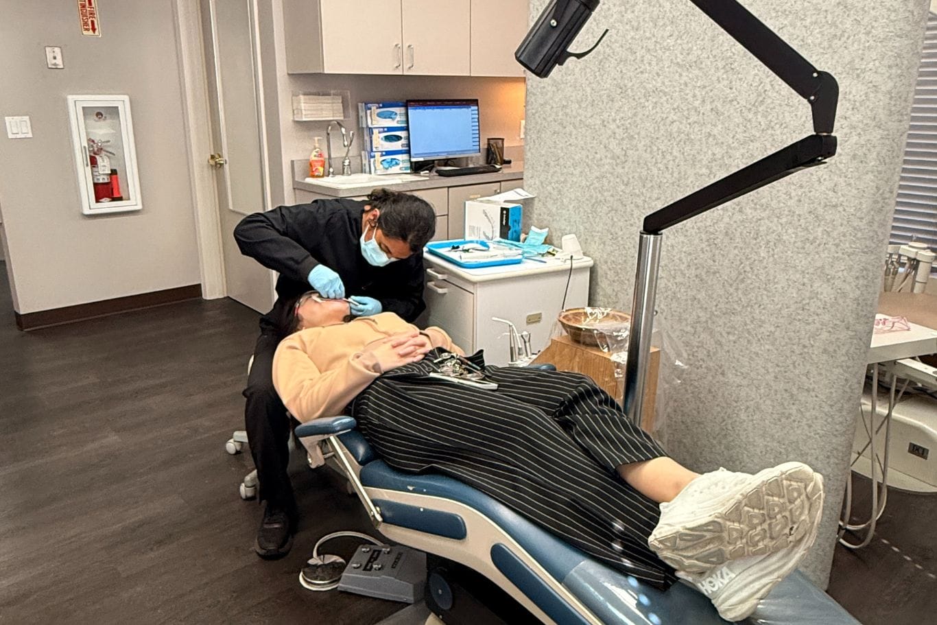 An orthodontist wearing gloves and a mask examines a patient lying in a dental chair in a modern San Jose Berryessa orthodontist office.