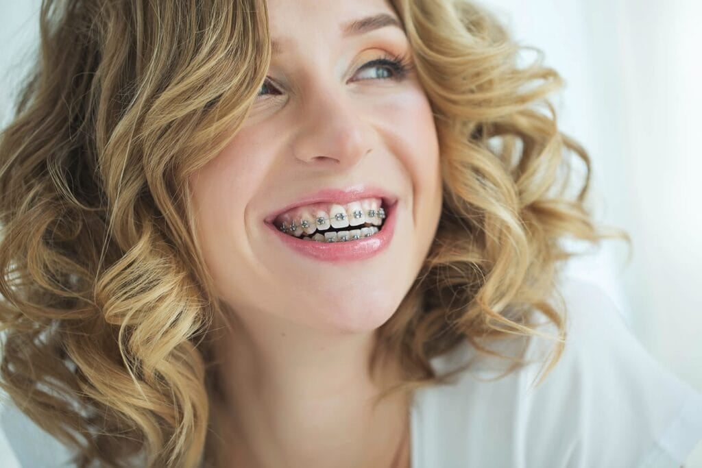 Contact us for different types of braces offered. Woman wearing metal braces.