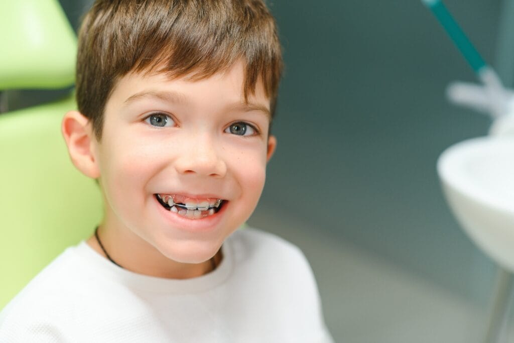 Smiling child wearing an orthodontic appliance at a dental clinic.