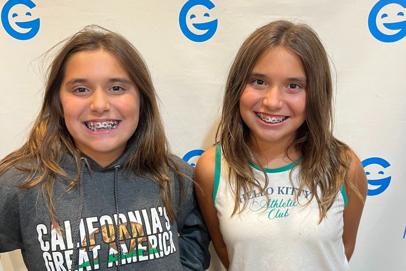 Two girls with long brown hair and braces stand side by side, smiling at Image Orthodontics San Jose Berryessa