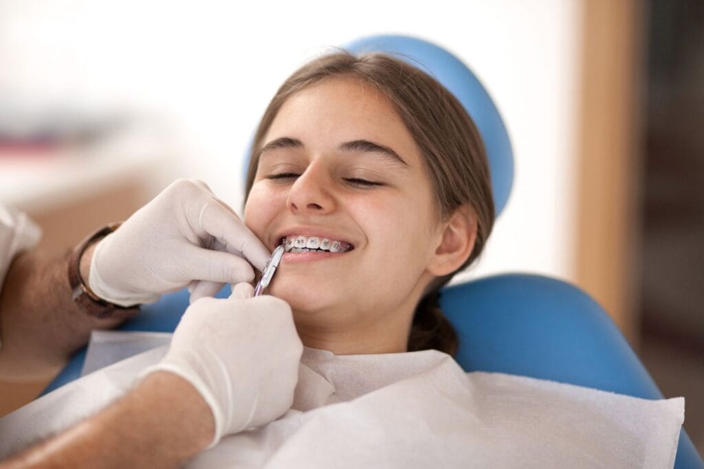 Orthodontist in San Francisco adjusting braces on a child patient who is sitting in an orthodontic chair