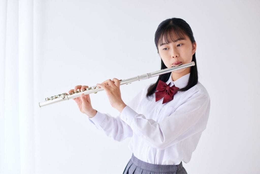 Teenage girl in a school uniform playing a flute
